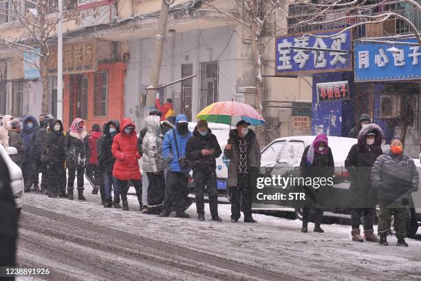 This photo taken on March 2, 2022 shows people queueing to undergo nucleic acid tests for the Covid-19 coronavirus as it snows in Harbin in China's...