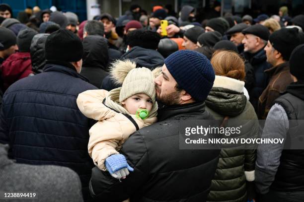 Man holds his child as families, who fled Ukraine due to the Russian invasion, wait to enter a refugee camp in the Moldovan capital Chisinau on March...