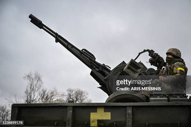 An Ukrainian soldier keeps position sitting on a ZU-23-2 anti-aircraft gun at a frontline, northeast of Kyiv on March 3, 2022. - A Ukrainian...