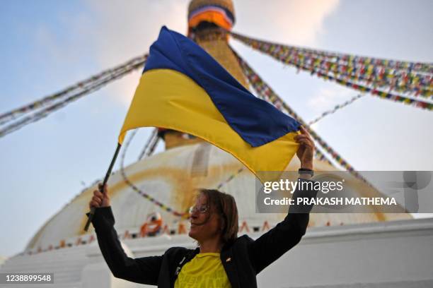 Diplomat from the German embassy in Nepal, holds a Ukraine's flag as she takes part in a candlelight vigil held in solidarity with the people of...