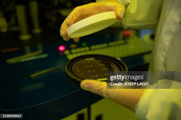 An employee holds a silicon wafer during the chips fabrication process at the Institute of Microelectronics of Barcelona in Bellaterra near...