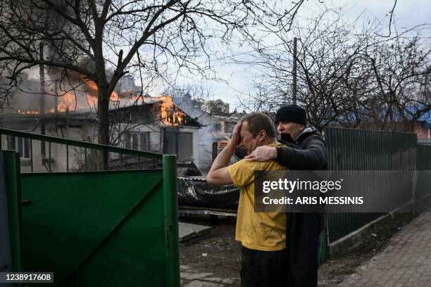 Yevghen Zbormyrsky is comfirted as he stands in front of his burning home after it was hit by a shelled in the city of Irpin, outside Kyiv, on March...