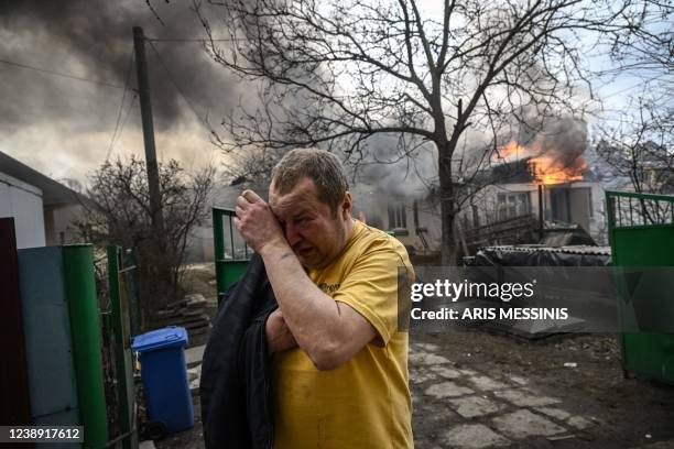 Yevghen Zbormyrsky reacts in front of his burning home after it was hit by a shelled in the city of Irpin, outside Kyiv, on March 4, 2022. - The UN...