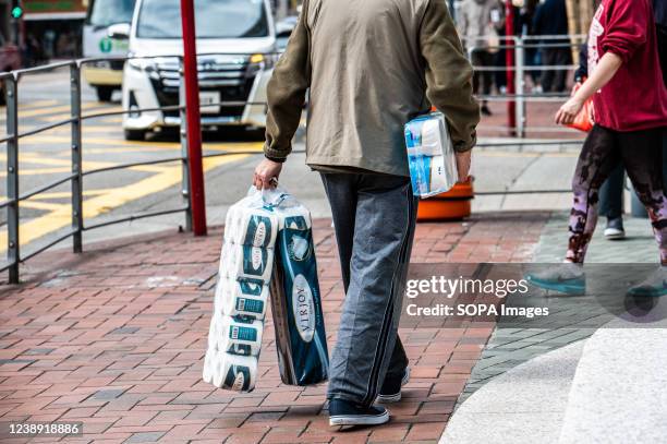 As panic buying hit Hong Kong, a man carries three dozen toilet paper rolls. In Hong Kong, rumors spread out that the government plans to impose a...