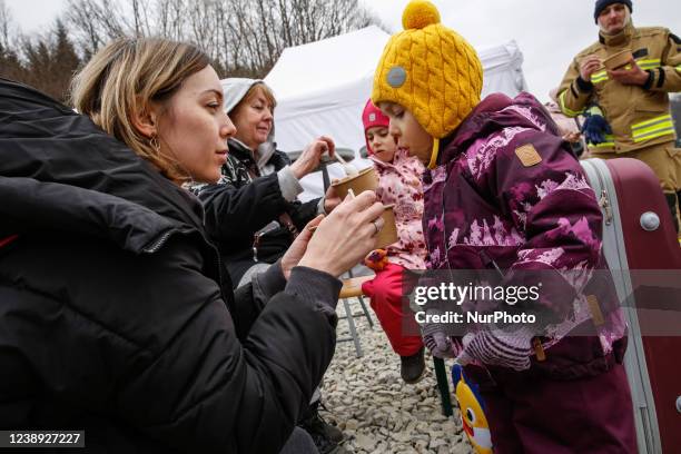 Ukrainian mother and grandmother give hot soup to children after arriving at the Polish border crossing in Kroscienko as Russian invasion forced many...
