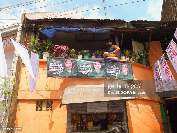 Young boy sits at the balcony of his house with large posters of Davao City Mayor Sara Duterte. Presidential daughter and Davao City Mayor Sara...