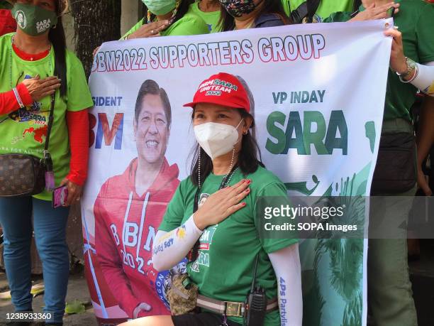 Supporter poses for pictures behind Bongbong Marcos Jr. And Sara Duterte's campaign banner. Presidential daughter and Davao City Mayor Sara...