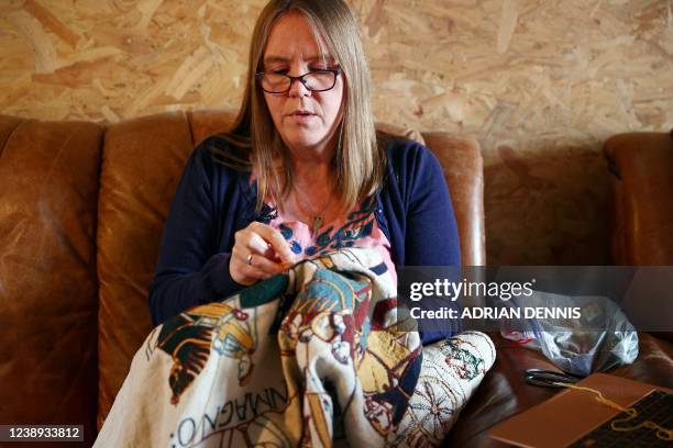 Mia Hansson sits on the couch at home while she works on her embroidery replica of The Bayeux Tapestry in Wisbech, east of England on February 24,...