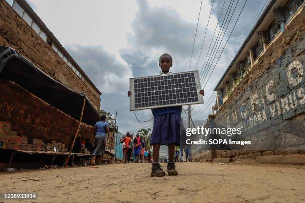 Young school girl seen carrying a Solar Panel by the streets in Kibera. In Kibera Slums, most residents especially the street vendors, private...