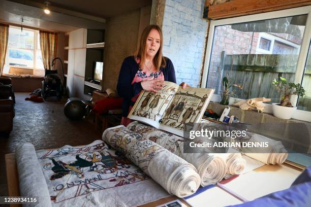 Mia Hansson looks at her embroidery replica of The Bayeux Tapestry at home in Wisbech, east of England on February 24, 2022. - Curled up on her sofa...