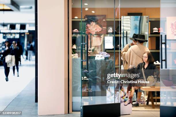 Shoppers try on shoes at Westfield Century City in Los Angeles on Friday, March 4, 2022. Los Angeles County ends indoor mask mandates today.