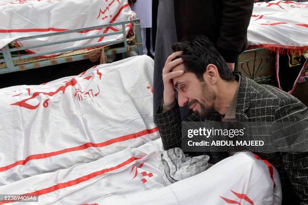 Man mourns next to the body of his relative who died in a bomb blast a day after a suicide attack at a Shiite mosque, during the funeral in Peshawar...