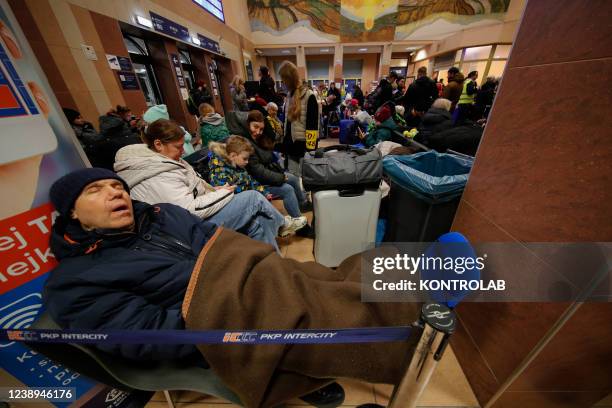 Ukrainian refugees tired from the long journey rest in the railway station of the city Rzeszow Glowny, near the border between Ukraine and Poland....