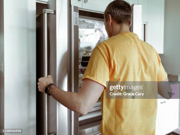 man searches refrigerator for food - refrigerator door stock pictures, royalty-free photos & images