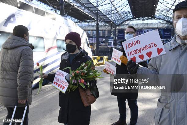 People holds signs reading "Welcome" and "Peace and Love" as people who arrived with the Allegro train from St Petersburg, Russia are welcomed and...