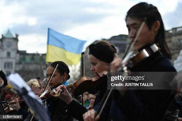 Ukrainian flag flutters in the breeze as dozens of musicians take part in a flashmob performance of "The Great Gate of Kyiv from pictures at an...