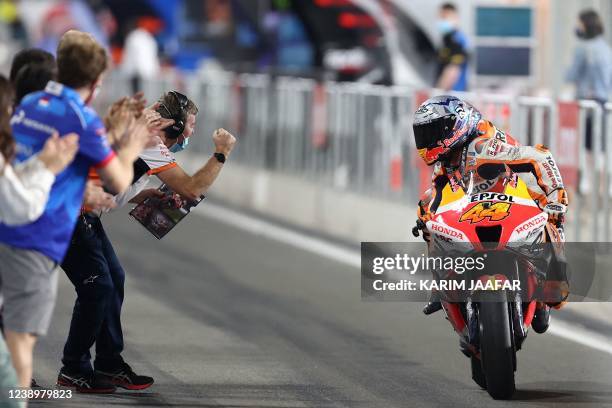 Repsol Honda Team's Spanish rider Pol Espargaro celebrates with teammates as he finishes third during the Moto GP Grand Prix of Qatar at the Lusail...