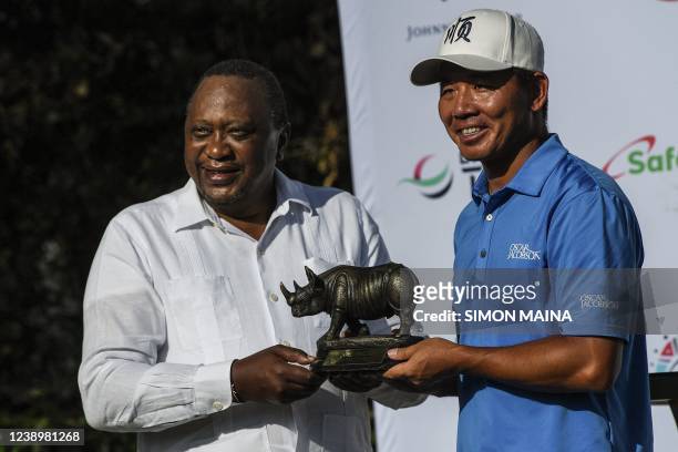 China's Ashun Wu holds the Magical Kenya Open trophy as he poses with Kenya's President Uhuru Kenyatta during the last day of the Magical Kenya Open...