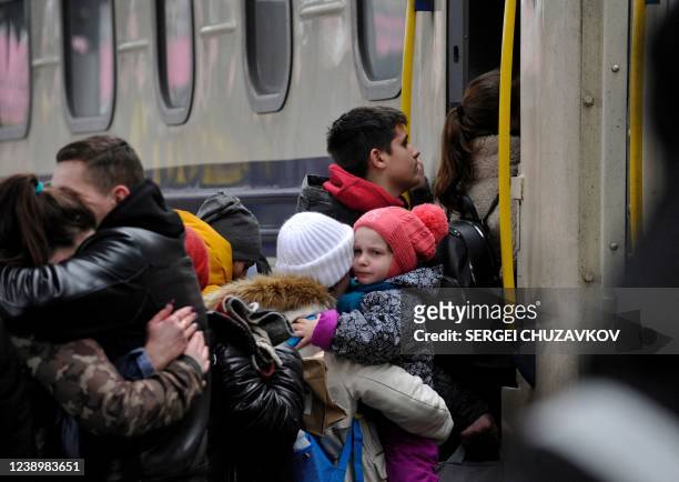 Woman holds a toddler before stepping up in an evacuation train at the central train station in Kyiv on March 6, 2022.