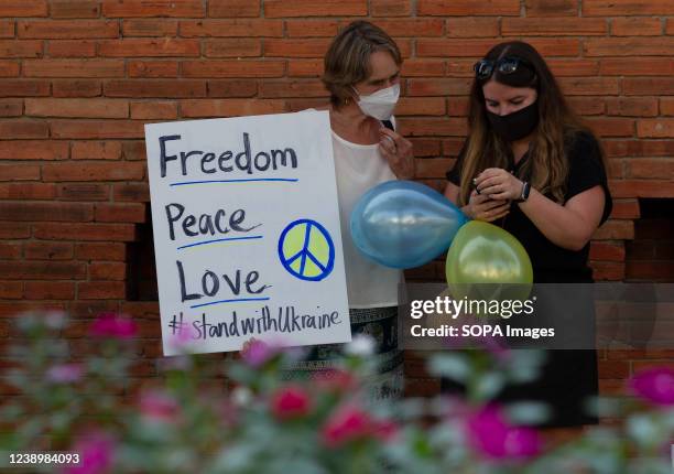Activists hold a placard saying "Freedom Peace Love" and balloons with Ukrainian colours, during during a peaceful demonstration against the Russian...