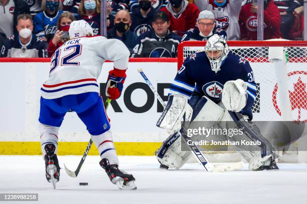 Goaltender Connor Hellebuyck of the Winnipeg Jets guards the net as Rem Pitlick of the Montreal Canadiens moves in for a second period penalty shot...