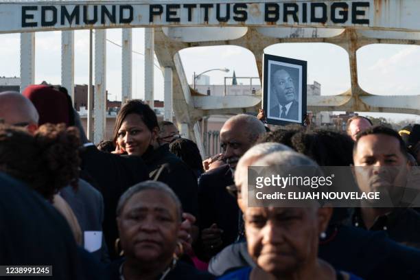 Person holds up a photo of late Reverend Martin Luther King Jr. While marching across the Edmund Pettus Bridge in commemoration of the 57th...