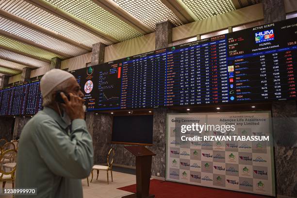 Stockbroker talks on his mobile phone as he monitors the latest share prices at the Pakistan Stock Exchange in Karachi on March 7, 2022.