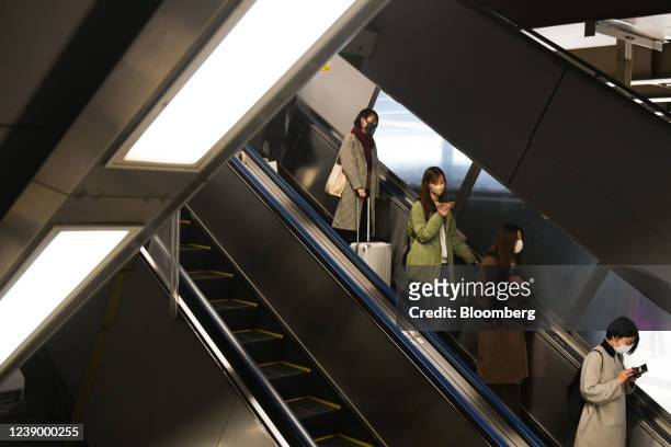 Morning commuters ride on an escalator in Tokyo, Japan on Monday, March 7, 2022. Japans decision to extend the duration of semi-emergency virus...
