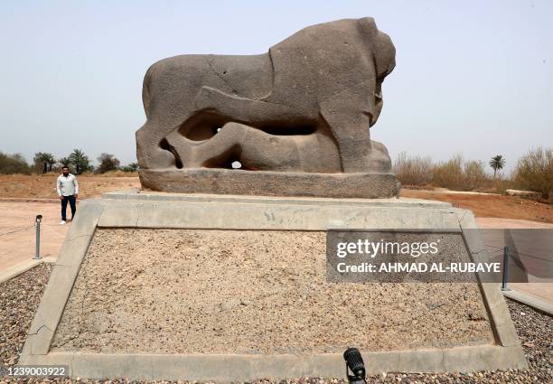 Man stands behind the statue of the Lion of Babylon at the ancient city of the same name -- a UNESCO World Heritage archaeological site -- in the...