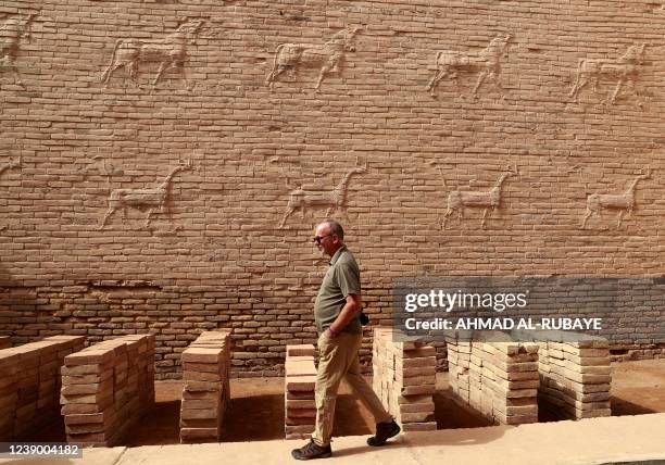 Foreign visitor walks on March 7, 2022 past ancient dragon figures in the ancient city of Babylon, a UNESCO World Heritage archaeological site, in...