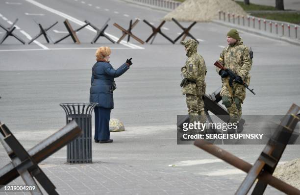 Local resident talks with members of the Ukrainian Territorial Defence Forces, the military reserve of the Ukrainian Armed Forces, next to anti-tank...