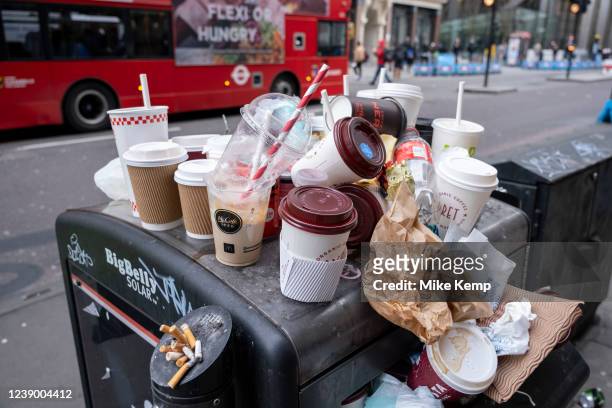 Coffee and soft drinks cups from some of the major take away food and drinks companies piled up on top of an overflowing street rubbish bin in the...