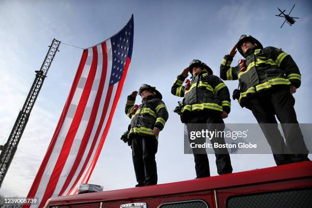 Medford, MA Medford firefighters salute from atop a ladder truck as the procession of State Police vehicles escorting deceased Massachusetts State...