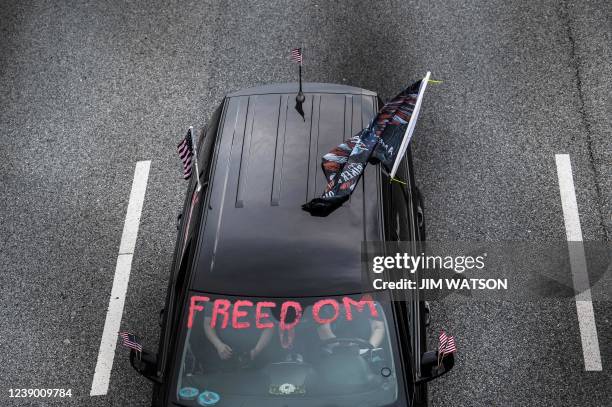 Demonstrators honk their horn while passing under an overpass in Lake Arbor, Maryland, on March 7 during "The People's Convoy" event. - The convoy...