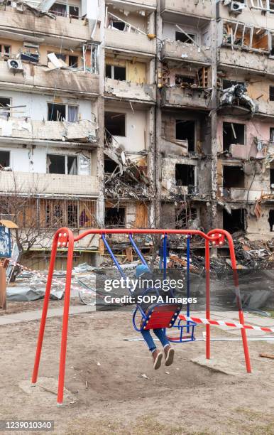 Kid plays on a playground swing next to a damaged residential building following a Russian shelling attack as Russian forces continue their...