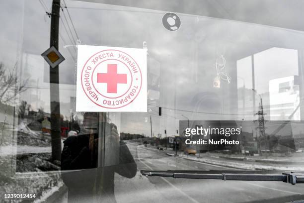 Sticker of the Ukrainian Red Cross Society is attached to the windscreen of one of the buses set to take off for besieged Mariupol to deliver...