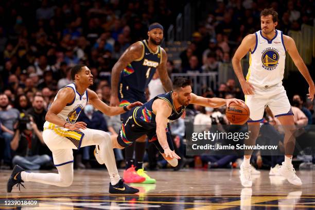 Facundo Campazzo of the Denver Nuggets and Jordan Poole of the Golden State Warriors battle for a loose ball at Ball Arena on March 7, 2022 in...