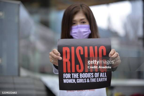 Japanese woman holds a banner to raise awareness about the status of women in Japan and around the world, during an event to celebrate the...