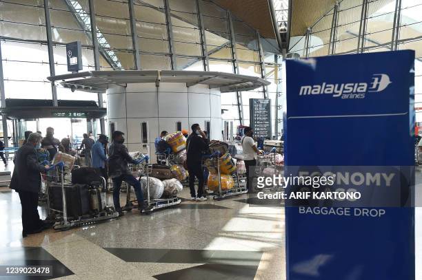 Passengers wait in line to drop off their luggage ahead of their departure from the Kuala Lumpur International Airport in Sepang on March 8 after...