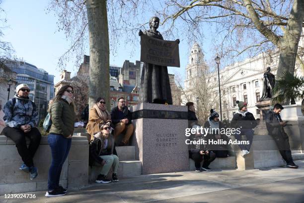 People sit beside the Millicent Fawcett statue in Parliament Square on International Women's Day, March 8, 2022 in London, England. Unveiled in April...