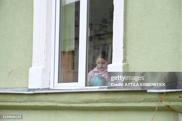 Girl plays with a globe next to the window of a class room in a school in Perekhrestya, close to the Ukrainian-Hungarian border on March 7 a refuge...