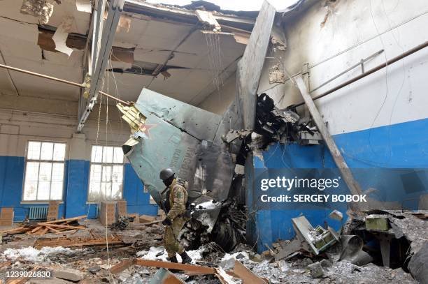 Member of the Ukrainian Territorial Defence Forces walks near remains of the Russian Sukhoi Su-25 assault aircraft crashed into the State Scientific...