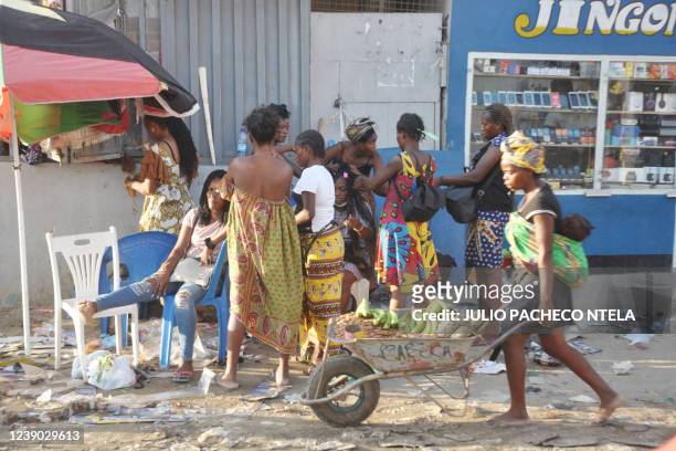 Street vendow pushes a wheelbarrow while carrying her son on her back in Luanda on March 8, 2022.