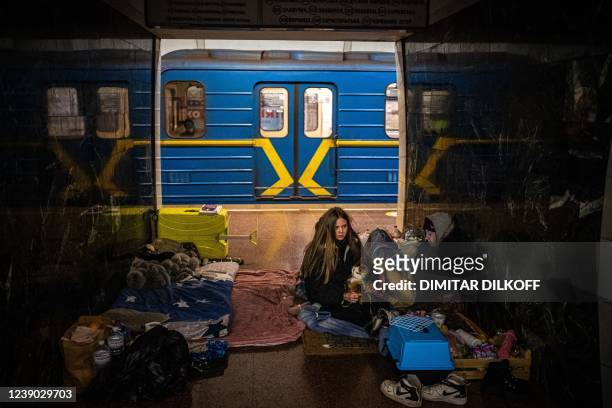Woman hugs her cat inside a subway carriage in a underground metro station used as a bomb shelter in Kyiv on March 8, 2022. - Ukraine's President...