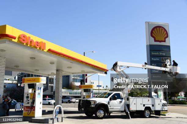 An electrical contractor repairs a sign with gasoline fuel prices above six and seven dollars a gallon at the Shell gas station at Fairfax and...