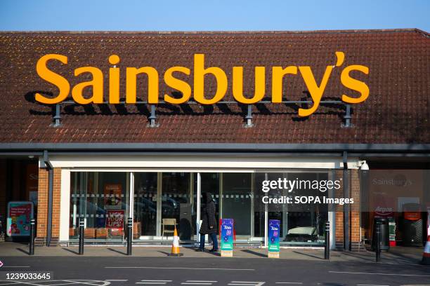 Woman walks past a branch of Sainsbury's supermarket.