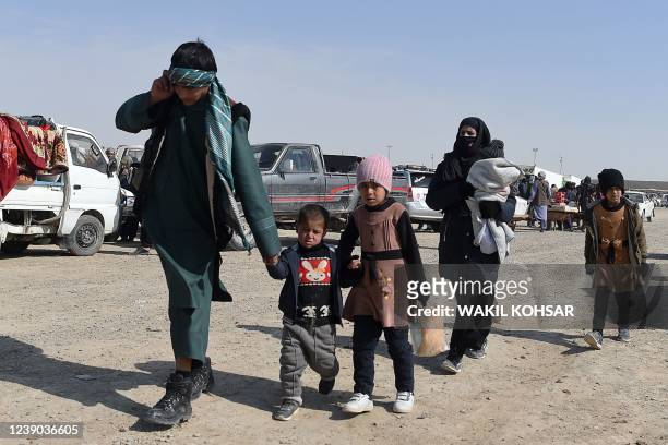 In this photo taken on February 17 an Afghan migrant family walks in a parking lot before leaving the country for Iran, in Zaranj in the southwestern...