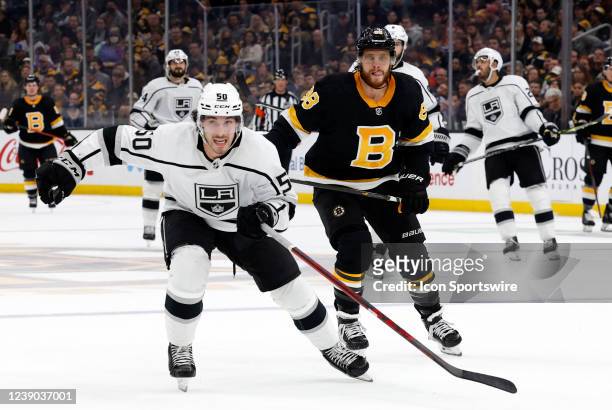 Los Angeles Kings defenseman Sean Durzi beats Boston Bruins right wing David Pastrnak to the puck during a game between the Boston Bruins and the Los...