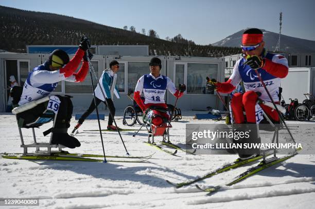 Chinas Zheng Peng, Liu Zixu and Mao Zhongwu relax after finishing the mens sprint sitting qualification cross-country skiing event on March 9, 2022...