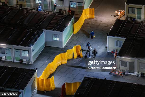 Healthcare workers wearing personal protective equipment escorts patients through a Covid-19 isolation facility in the Tsing Yi area in Hong Kong,...